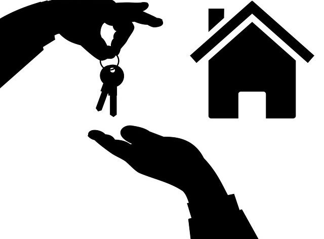 Hands passing keys to a new home.